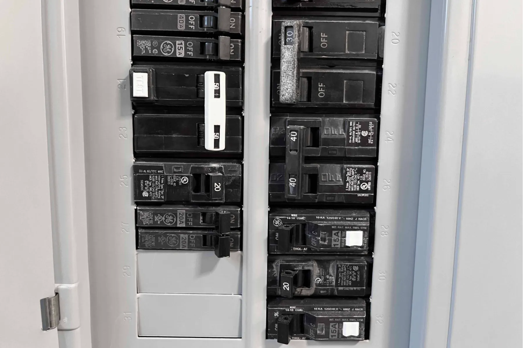 A close-up view of a circuit breaker panel with various switches labeled by amperage, some in the ON position and some in the OFF position.