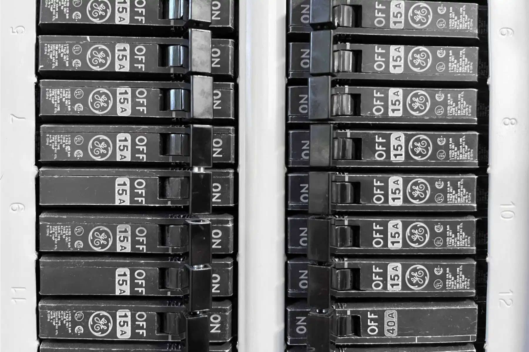 Close-up view of an electrical breaker panel with multiple circuit breakers labeled 15A, arranged in two vertical rows.