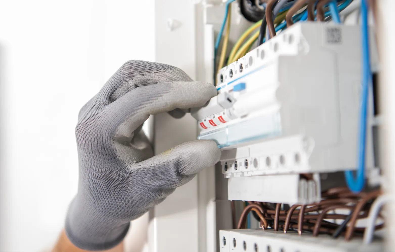 Gloved hand adjusting a circuit breaker in an electrical panel with visible wires and switches, illustrating when an electrical panel upgrade may be needed in Fraser Valley homes.